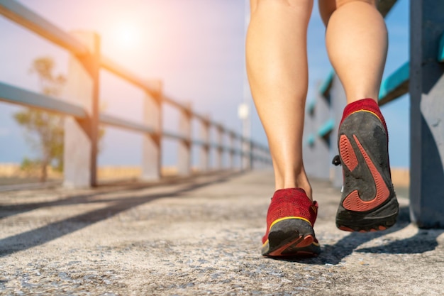 Donna indossare scarpe da corsa per camminare e correre su sfondo verde naturaEsercizio di salute