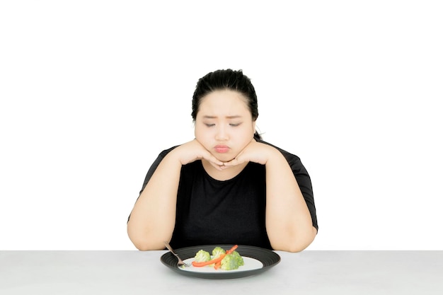 Donna infelice che mangia cibo sano in studio