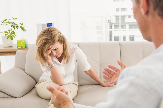 Donna infelice che si siede sul divano e parlando con terapeuta