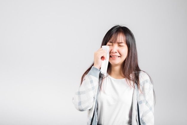 Donna infelice di cattivo umore il suo pianto pulisce il muco con il tessuto, la bella giovane donna stress sente starnutire il seno usa l'asciugamano per asciugare la lacrima dagli occhi, girato in studio isolato su sfondo bianco con spazio di copia