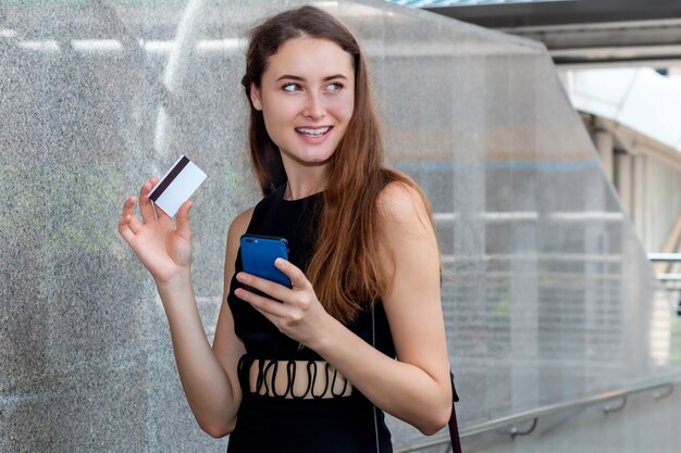 Donna intelligente che compra online con una carta di credito e un'applicazione per smartphone.