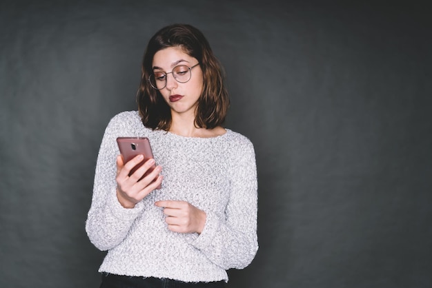 Donna intelligente con telefono cellulare che guarda le informazioni