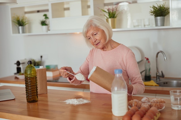 Donna invecchiata diligente che cucina a casa cucina