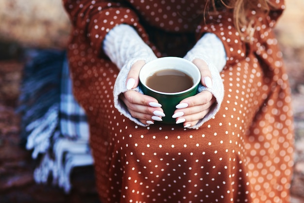 Donna irriconoscibile che beve caffè nella foresta