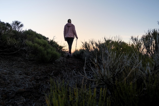 donna irriconoscibile che cammina sulla montagna al tramonto