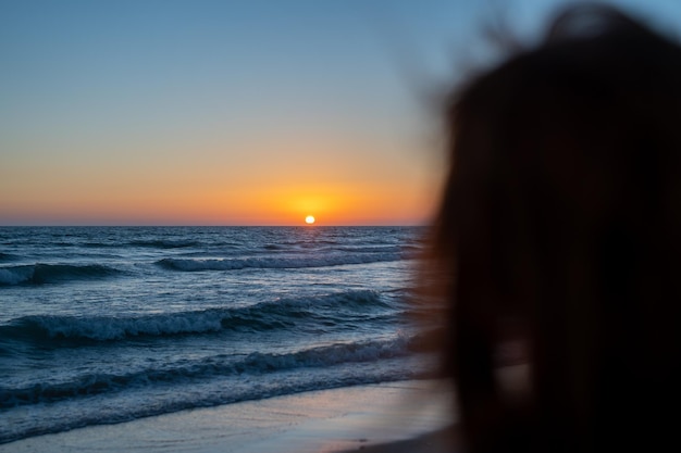 Donna irriconoscibile che guarda un tramonto al mare