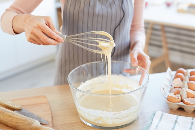 Donna irriconoscibile che produce pasta per cupcakes utilizzando la frusta, colpo di alto angolo orizzontale