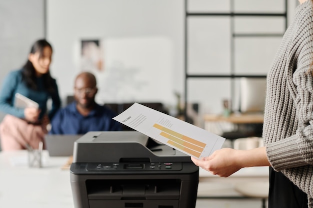 Donna irriconoscibile che stampa documenti in un ufficio moderno