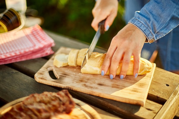 Donna irriconoscibile che taglia il pane per bruschetta su tavola di legno