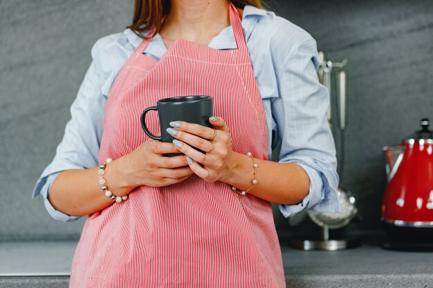 Donna irriconoscibile che tiene una tazza di caffè mentre si trovava in cucina