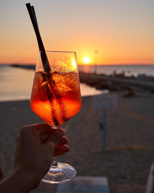 Donna irriconoscibile con in mano un bicchiere di Spritz cocktail tradizionale con alcol in un bar sulla spiaggia