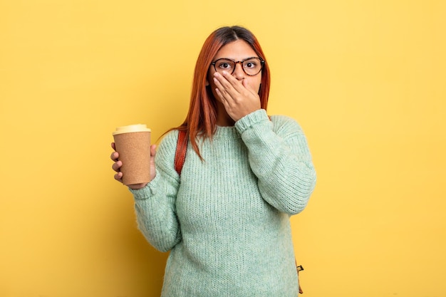 Donna ispanica che copre la bocca con le mani con uno shock. studente con un concetto di caffè