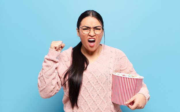 Donna ispanica che grida in modo aggressivo con un'espressione arrabbiata o con i pugni chiusi per celebrare il successo