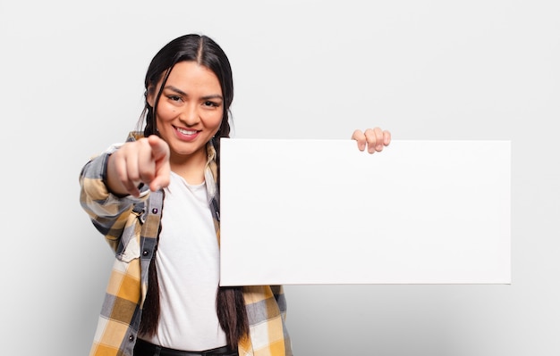 Donna ispanica che punta alla telecamera con un sorriso soddisfatto, fiducioso, amichevole, scegliendo te