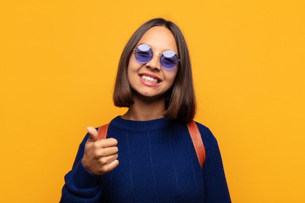 Donna ispanica che si sente orgogliosa, spensierata, sicura e felice, sorridendo positivamente con i pollici in su