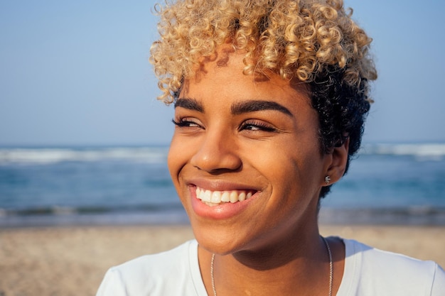 Donna ispanica latina con pelle perfetta e capelli ricci afro godendo in spiaggia