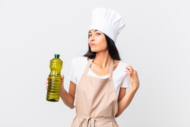 Donna ispanica piuttosto chef in possesso di una bottiglia di olio d'oliva.