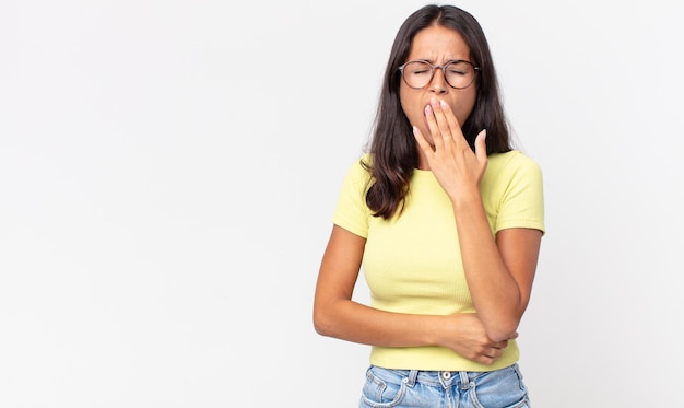 Donna ispanica piuttosto magra che sbadiglia pigramente la mattina presto stanca e annoiata