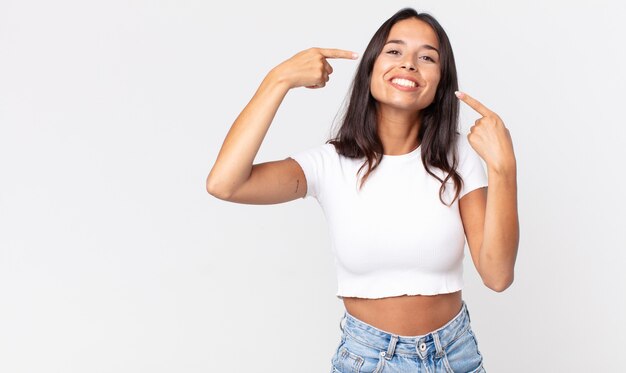 Donna ispanica piuttosto magra che sorride con sicurezza indicando il proprio ampio sorriso