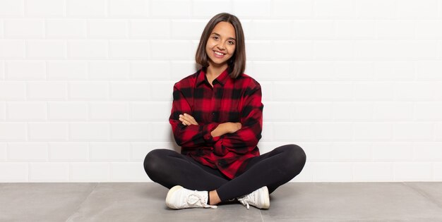 Donna ispanica sorridente con le braccia incrociate e un'espressione felice, fiduciosa, soddisfatta, vista laterale