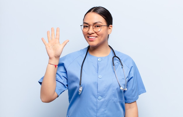 Donna ispanica sorridente e dall'aspetto amichevole, che mostra il numero cinque o quinto con la mano in avanti, conto alla rovescia