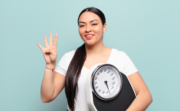 Donna ispanica sorridente e dall'aspetto amichevole, mostrando il numero quattro o quarto con la mano in avanti