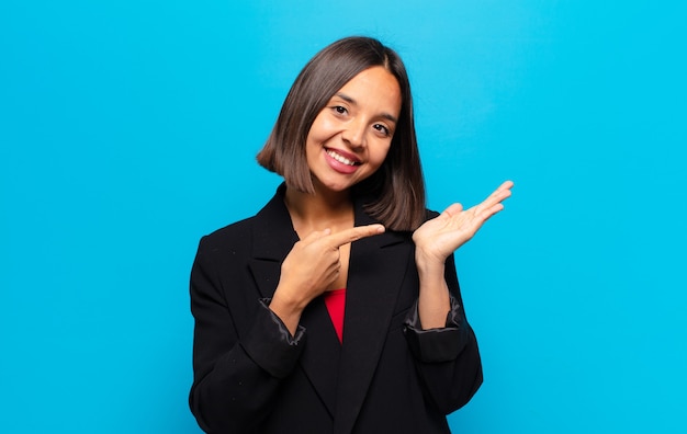 Donna ispanica sorridente, sentendosi felice, spensierata e soddisfatta, indicando un concetto o un'idea sullo spazio della copia sul lato