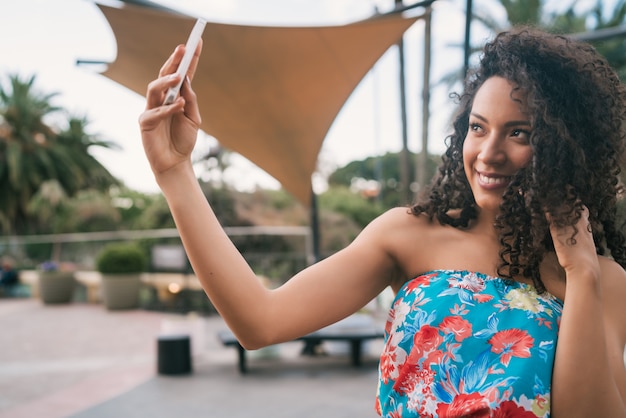 Donna latina afroamericana che prende un selfie con il telefono.
