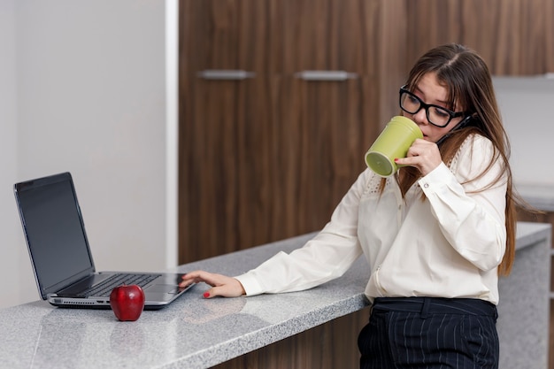 Donna latina che beve caffè mentre lavora al suo computer concetto di essere a casa