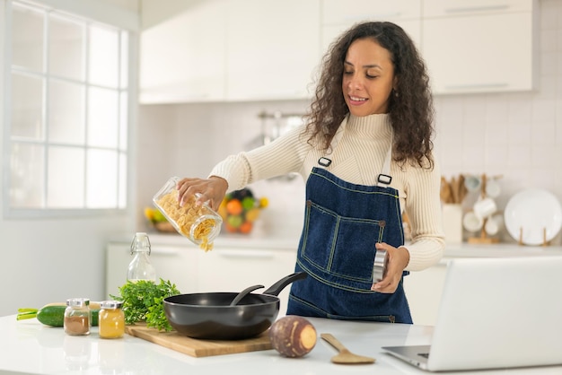 Donna latina che gira video e cucina in cucina