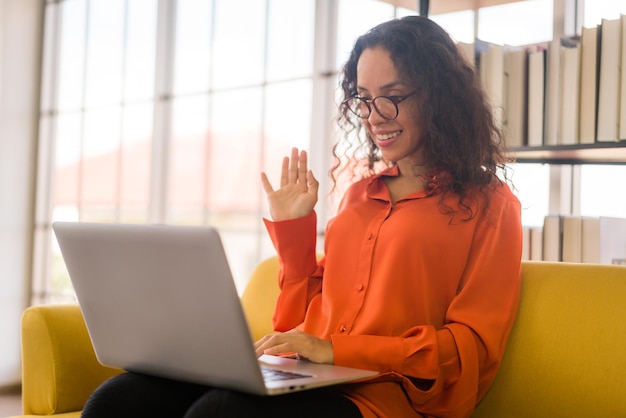 Donna latina che lavora con il computer portatile sul divano