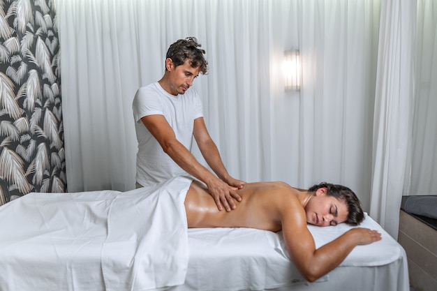 Donna latina che riceve un massaggio alla schiena al centro benessere da un massaggiatore maschio. Concetto di spa.