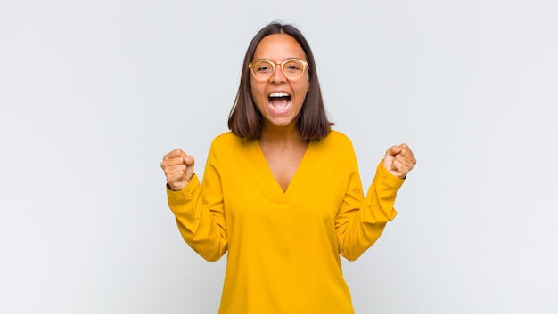 Donna latina che si sente felice, sorpresa e orgogliosa, grida e celebra il successo con un grande sorriso