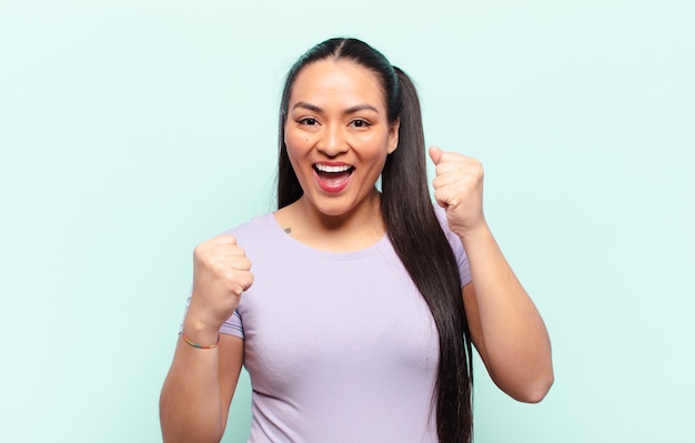 Donna latina che si sente felice, sorpresa e orgogliosa, grida e celebra il successo con un grande sorriso