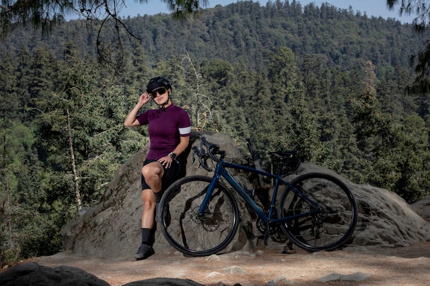 Donna latina con bicicletta che riposa nella foresta con un paesaggio di alberi sullo sfondo