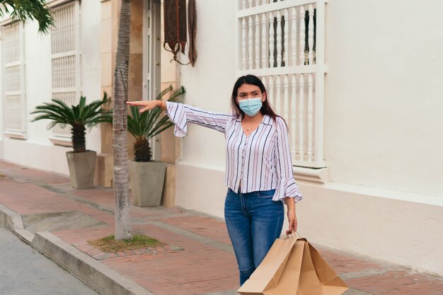 Donna latina con maschera che chiama un taxi.