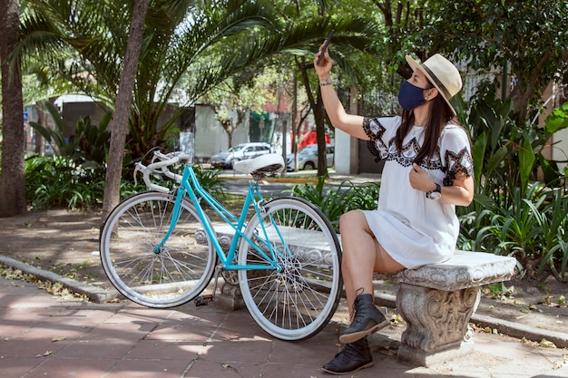 Donna latina con maschera che si fa un selfie seduta su una panchina dopo aver camminato