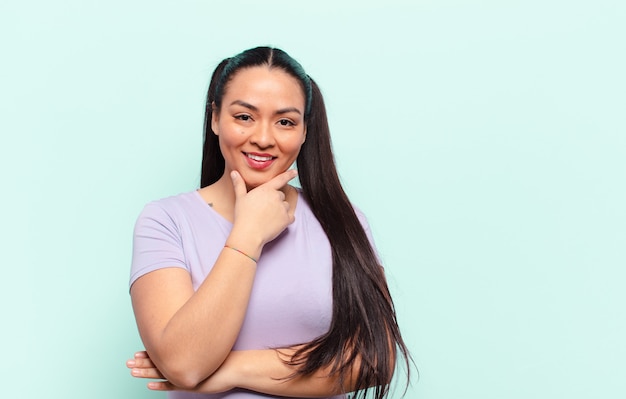 Donna latina sorridente, godersi la vita, sentirsi felice, amichevole, soddisfatta e spensierata con la mano sul mento