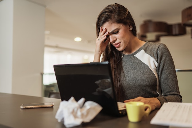 Donna latina stressata che soffre di emicrania con un laptop