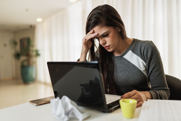 Donna latina stressata che soffre di emicrania con un laptop