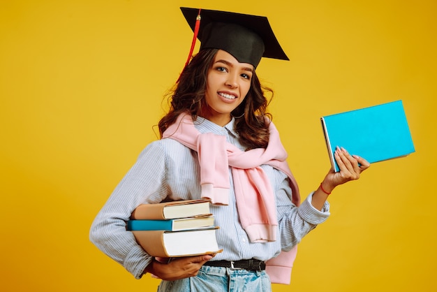 Donna laureata in un cappello di laurea in testa, con libri su giallo.