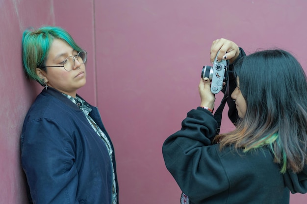 Donna lesbica che scatta un ritratto del suo partner con una fotocamera digitale in strada