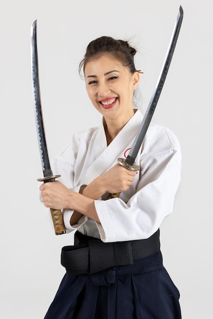 Donna maestro di aikido nel tradizionale kimono samurai hakama con cintura nera con spada katana su bianco