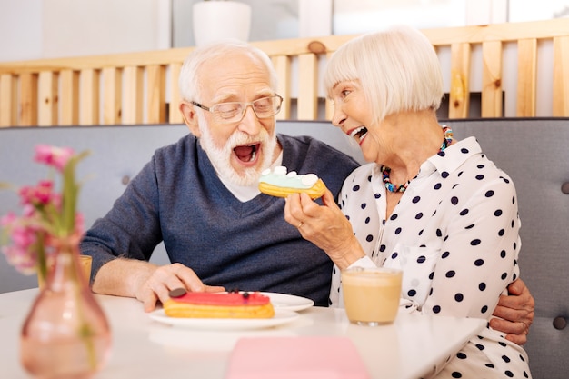 Donna maggiore allegra che trasporta eclair e uomo anziano che la morde