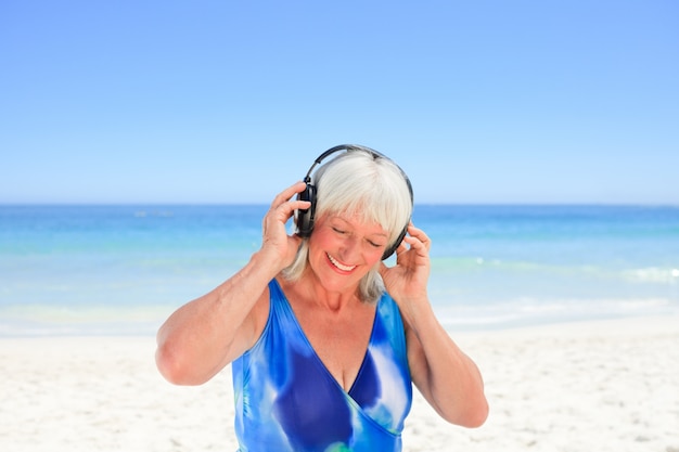 Donna maggiore che ascolta una certa musica al lato del mare