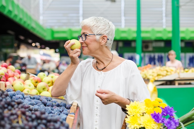 Donna maggiore che compra frutta sul mercato