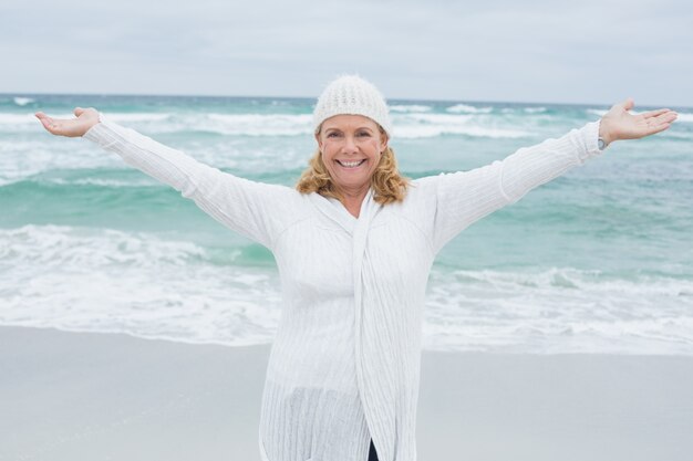 Donna maggiore con le braccia tese in spiaggia