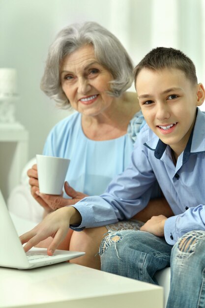 Donna maggiore con suo nipote che utilizza insieme il computer portatile