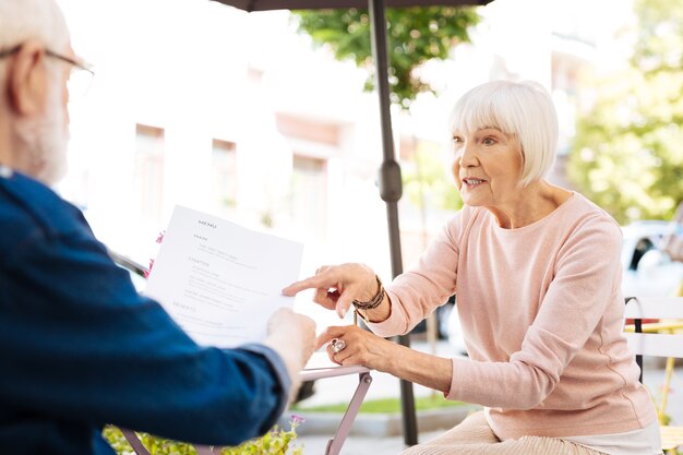 Donna maggiore concentrata che parla all'uomo che tiene la carta