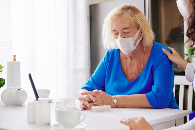 Donna maggiore triste nella mascherina medica